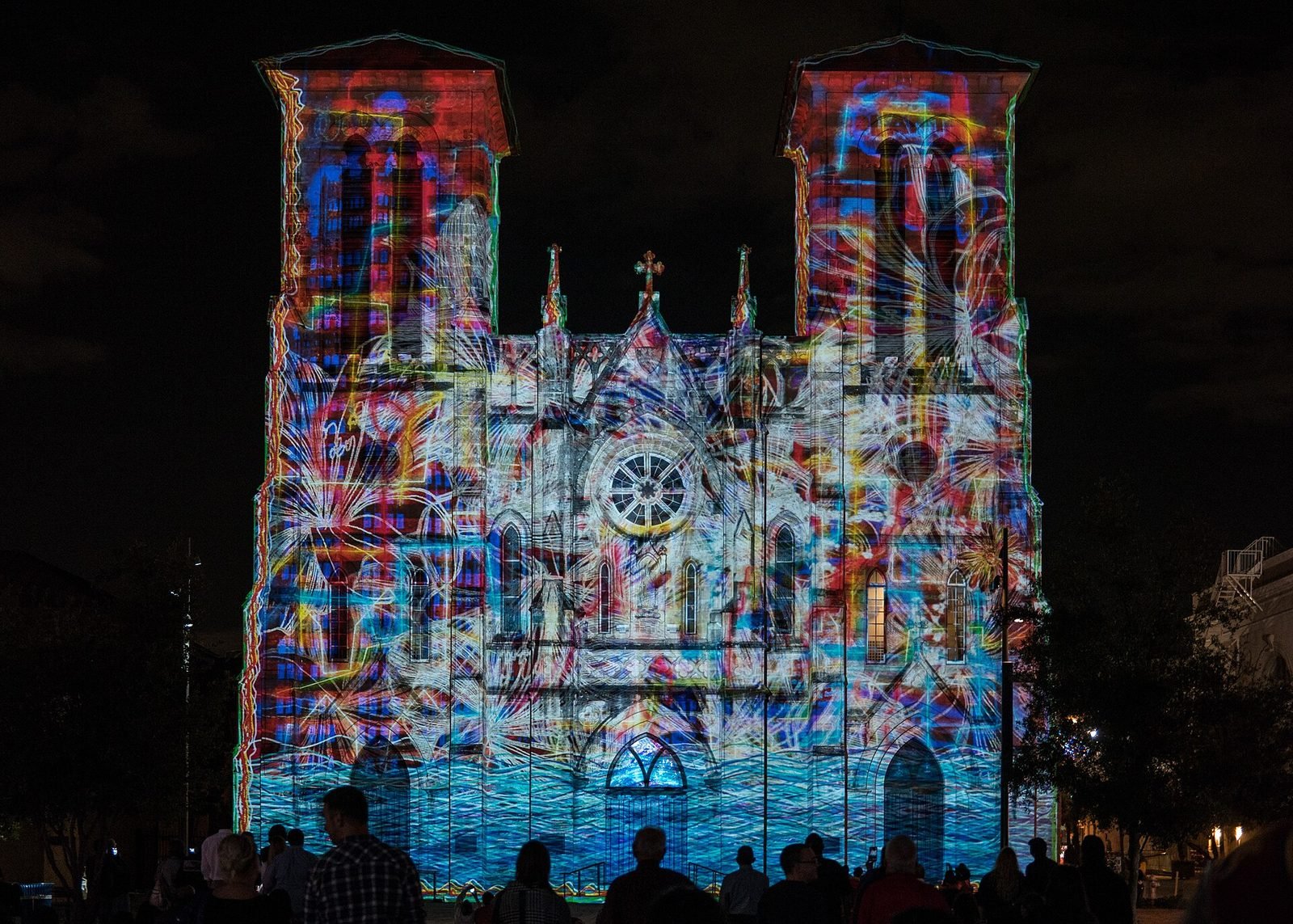 A cathedral facade covered in colourful projection mapping at night