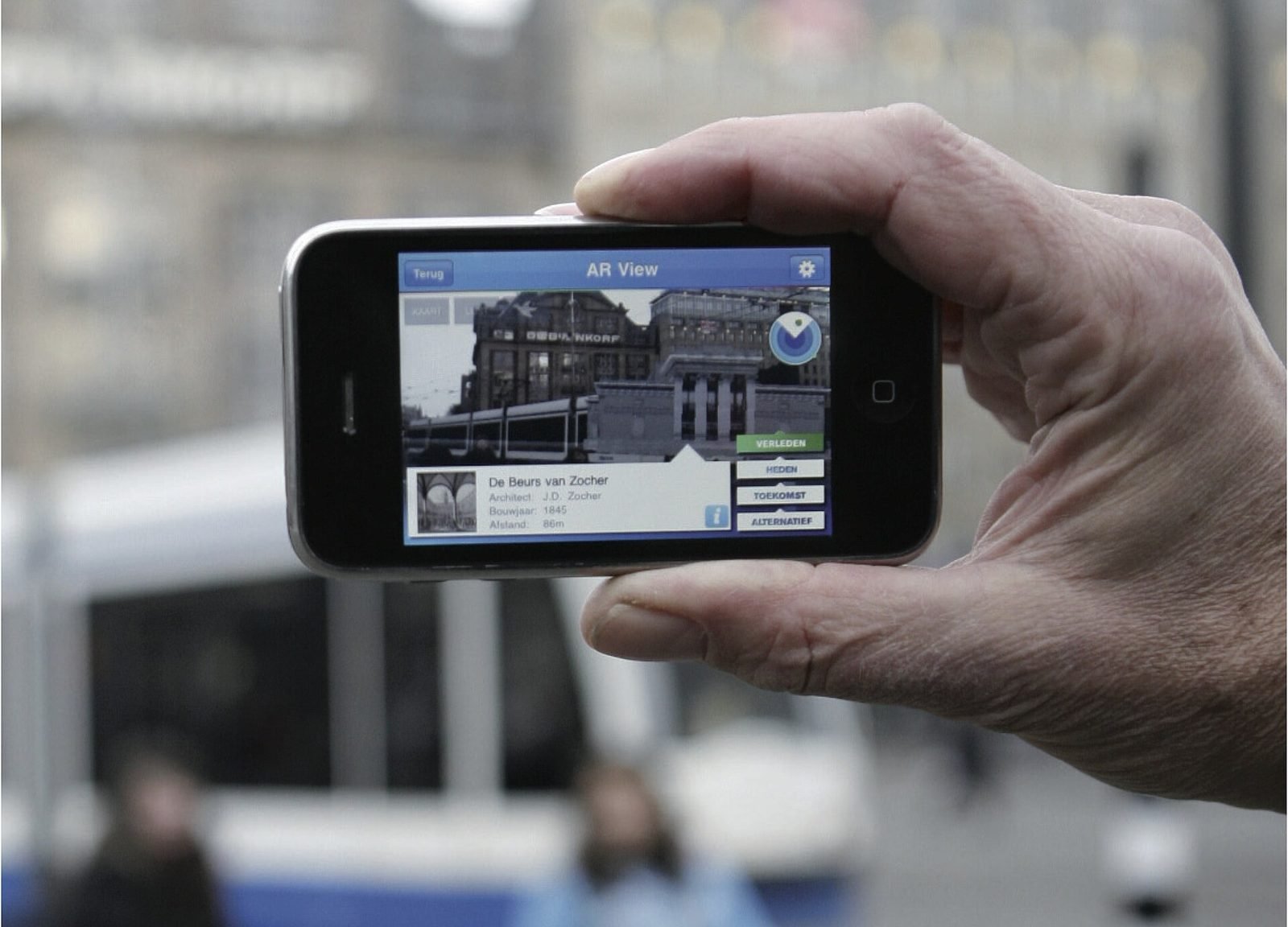 A smartphone held up on a city street showing an augmented reality layer over the buildings