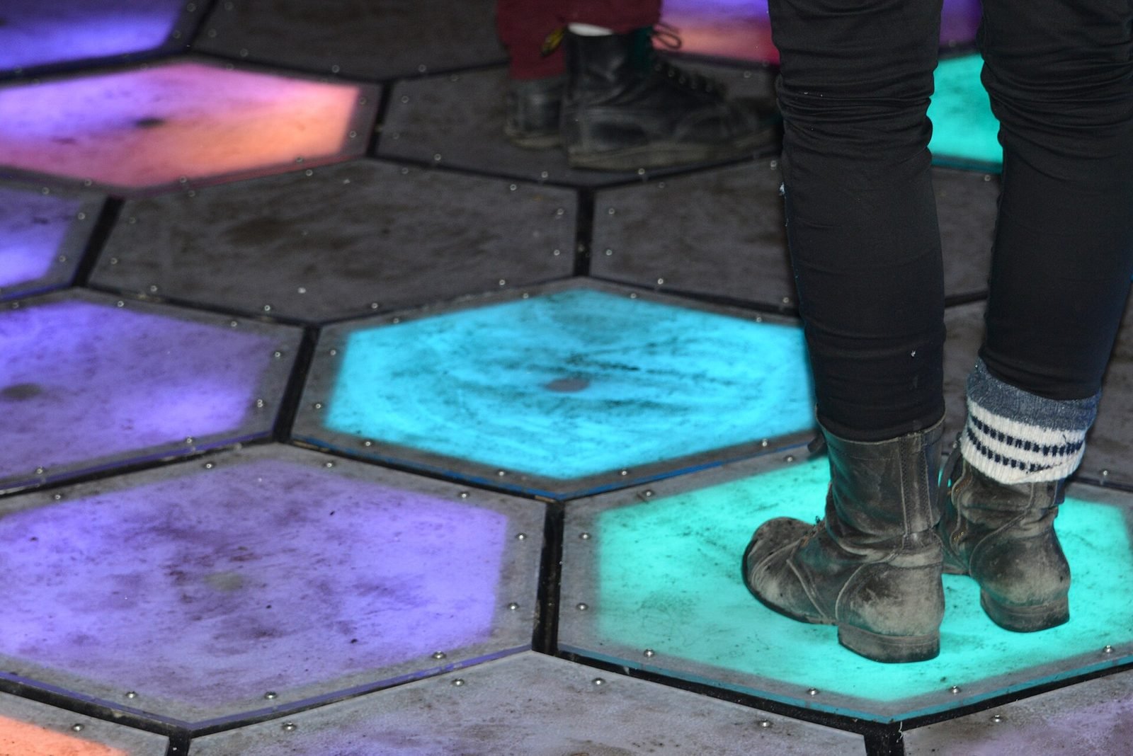 Visitors standing on an interactive floor of glowing hexagonal tiles